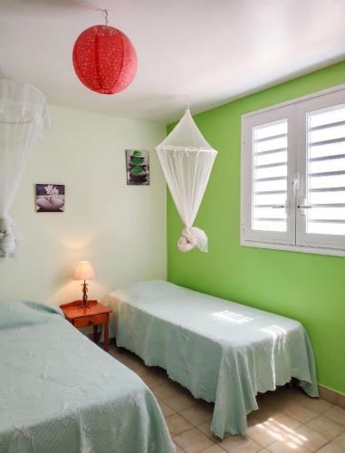 a green room with two beds and a window at Appartement confortable à Sainte-Anne, 70m², vue jardin in Sainte-Anne