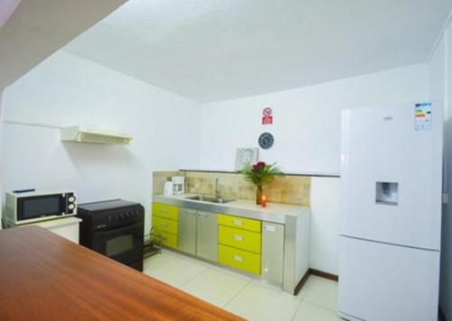 a kitchen with yellow cabinets and a white refrigerator at Modern Apartment in Pereybere + Pool in Pereybere