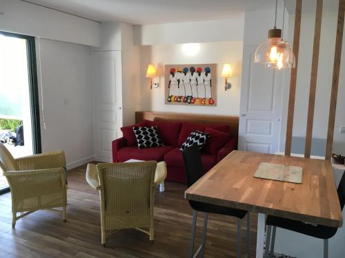 a living room with a red couch and a table at Appartement cosy à Saint-André-des-Eaux de 47 m² avec jardin in Saint-André-des-Eaux