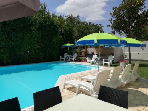 a swimming pool with chairs and umbrellas next to it at Comfortable Villa in Ragusa with Pool in Trecasuzze