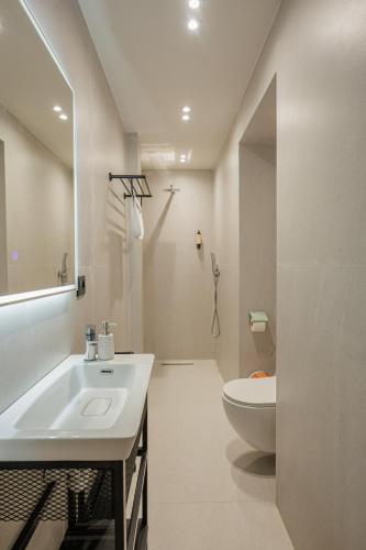 a white bathroom with a sink and a toilet at Dreamscape Central in Tirana