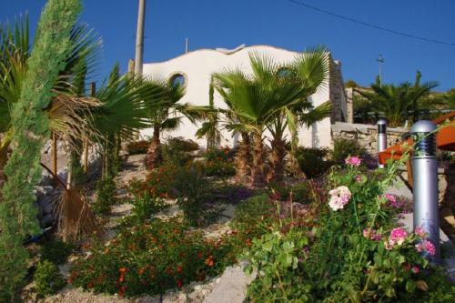a garden with flowers and palm trees in front of a building at Spacious villa with private pool and stunning views in Bompensiere