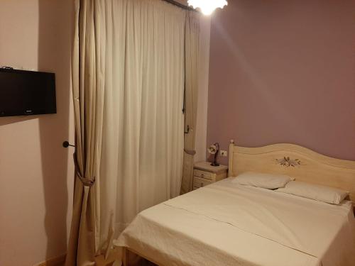 a bedroom with a white bed and a curtain at Spacious villa with private pool and stunning views in Bompensiere