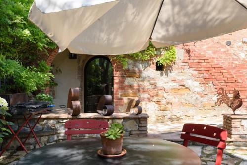 a patio with a table and an umbrella at Charming House in Trequanda with Shared Pool in Trequanda