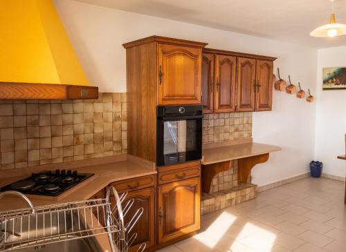 a kitchen with wooden cabinets and black appliances at Appartement lumineux aux Trois-Îlets in Les Trois-Îlets