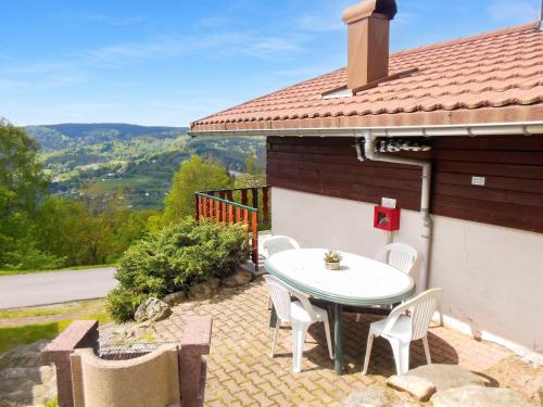 a patio with a table and chairs on the side of a house at Chalet charmant au Tholy avec piscine partagée in Le Tholy