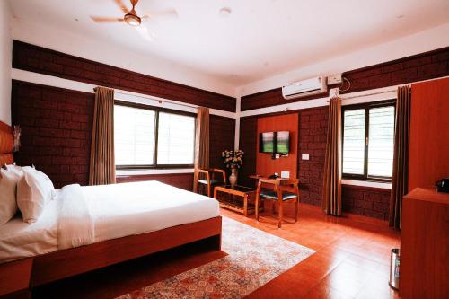 a bedroom with a bed and a desk in it at Apoorva River Resort in Māvingundi