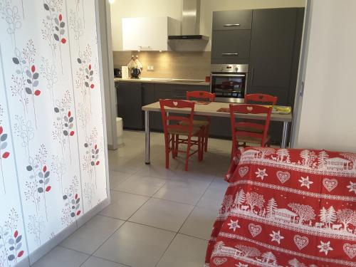 a kitchen with red chairs and a table in a kitchen at Appartement cosy avec piscine privée à Métabief - 38 m² in Métabief