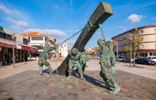 a statue of three people holding up a sign at Comfortable House in Marinhas + Garden and Sea View. in Marinhas