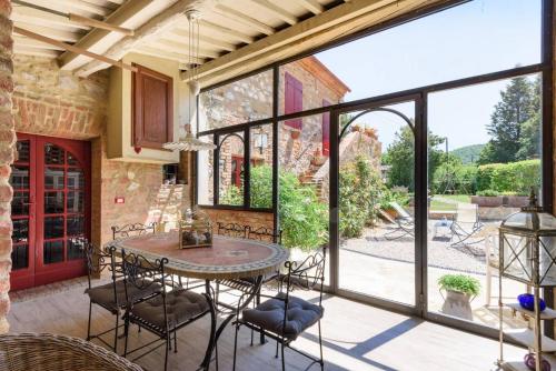 a patio with a table and chairs and a large window at Charming House in Trequanda + Pool in Trequanda