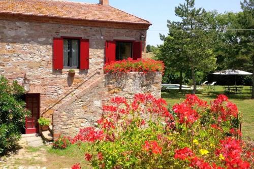 an old stone house with red windows and flowers at Charming House in Trequanda + Pool in Trequanda