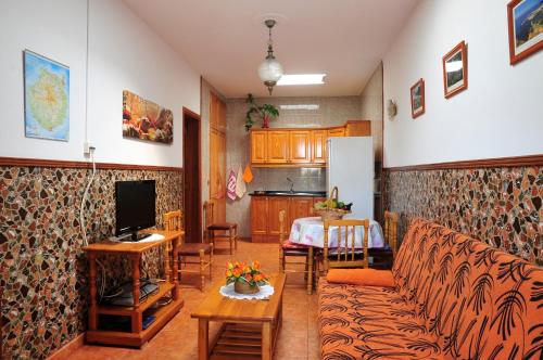 sala de estar con sofá, mesa y cocina en Apartamentos Buen Leon, en Playa de Tasarte