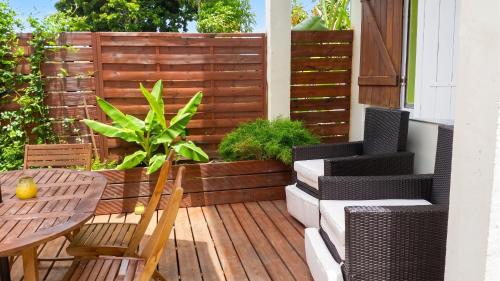 a patio with a wooden deck with a table and chairs at Appartement Privilégié Le Moule 70 m² + Piscine in Le Moule