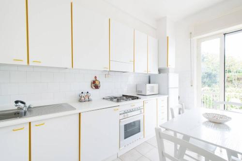 a white kitchen with white cabinets and a table at Charming apartment in Vieste with balcony and garden view in Vieste