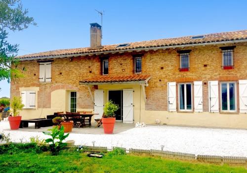a large brick house with a patio in front of it at Studio charmant à Saint-Jory, 25 m², piscine partagée in Saint-Jory