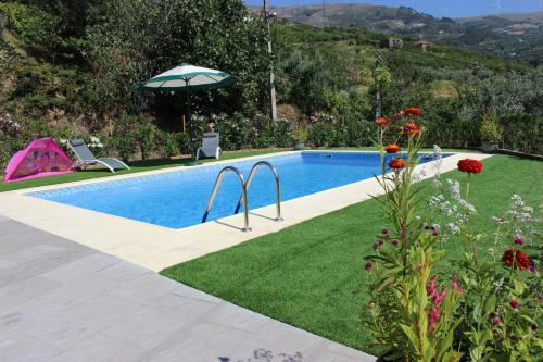 a swimming pool in a garden with a lawn and an umbrella at Peaceful villa in São Martinho de Mouros with private pool in Frende
