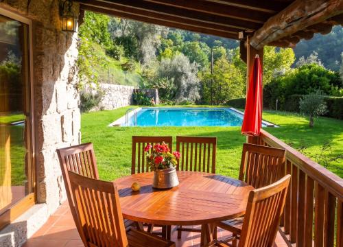 a wooden table and chairs on a porch with a pool at Elegant Villa with Panoramic Views in Caniçada in Caniçada