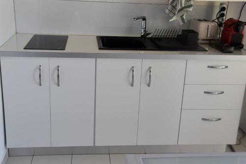 a kitchen with white cabinets and a sink at Studio moderne à Baie Mahault 27 m² avec balcon agréable in Baie-Mahault