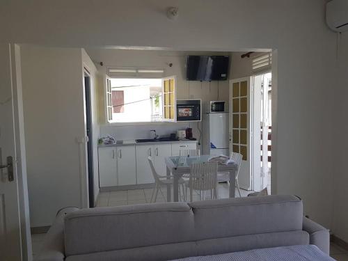a living room with a couch and a table and a kitchen at Studio moderne à Baie Mahault 27 m² avec balcon agréable in Baie-Mahault