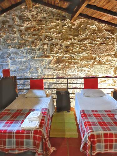 two beds in a room with a stone wall at Cozy house in Águeda 45 m² with shared pool in Urgueira