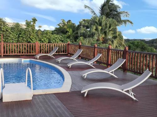 a group of chairs sitting around a swimming pool at Villa de charme à Sainte-Anne avec piscine privée in Sainte-Anne