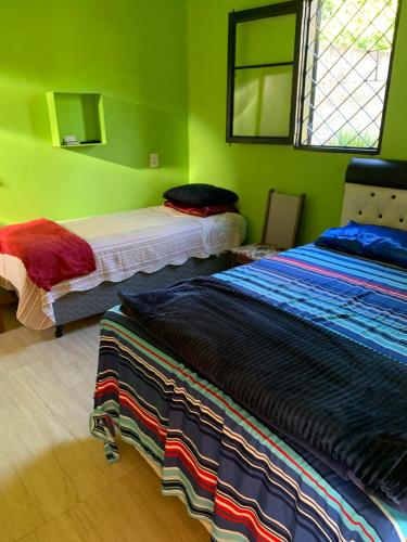 two beds in a room with green walls at Recanto Pedrita in Pedreira