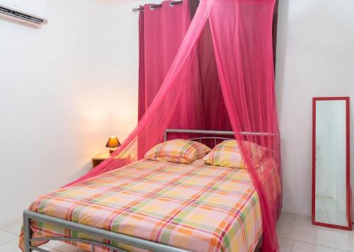 a bed with a pink canopy in a room at Appartement moderne à Le Lamentin avec jardin clos, 110 m² in Le Lamentin