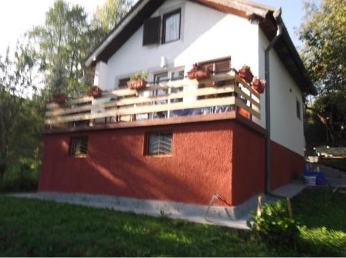 a red and white house with a balcony at Cozy House in Jazvine with Garden in Jazvine