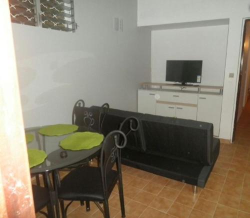 a dining room with a table and a tv at Appartement moderne à Schoelcher avec terrasse et vue mer in Schœlcher