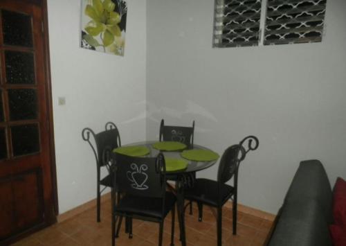 a dining room with a green table and black chairs at Appartement moderne à Schoelcher avec terrasse et vue mer in Schœlcher