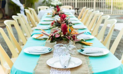 a long blue table with plates and flowers on it at Spacious apartment in Pereybere, 100 m² with shared pool in Pereybere