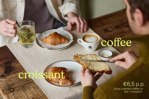 a person eating food at a table with coffee and croissants at Pods by The Usual Rotterdam in Rotterdam