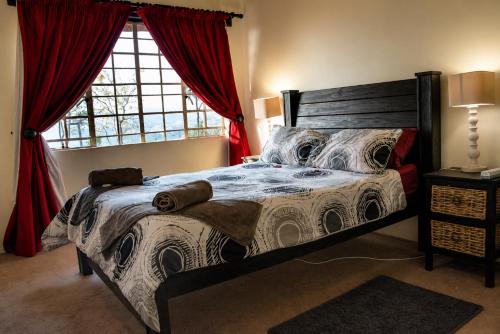 a bedroom with a large bed with red curtains at OPPIBERG GUEST HOUSE and SPA in Hartbeespoort