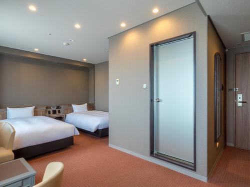 a hotel room with two beds and a sliding glass door at Hotel Global View Nagaoka in Nagaoka