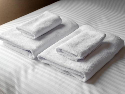 three towels are sitting on top of a bed at Hotel Global View Nagaoka in Nagaoka