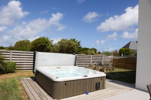 a hot tub sitting on a deck in a yard at Villa Yana Bretagne Piscine Intérieure partagée et Spa Privatif 100m de la Plage in Sibiril