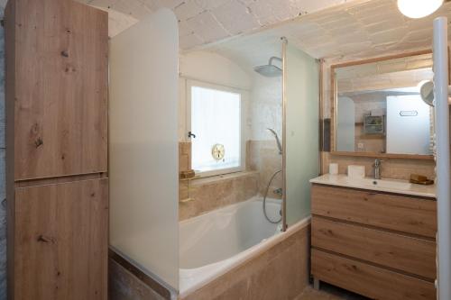 a bathroom with a tub and a sink at Maison Henriette - Authentique maison ardéchoise in Labeaume