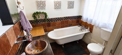 a bathroom with a tub and a toilet and a sink at OPPIBERG GUEST HOUSE and SPA in Hartbeespoort
