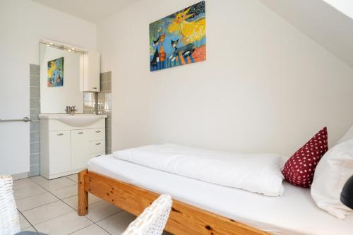 a bedroom with a bed with white sheets and red pillows at Sonneneck in Westerland