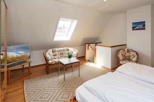 a bedroom with a bed and two chairs and a tv at Sonneneck in Westerland