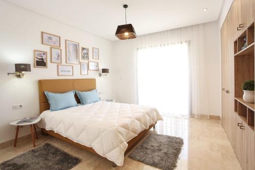 a white bedroom with a large bed with blue pillows at La Brise De Gammarth in Gammarth
