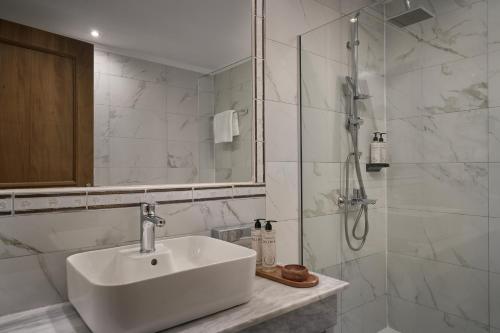 a white bathroom with a sink and a shower at Mythos Palace Resort - Adults Only in Boukari