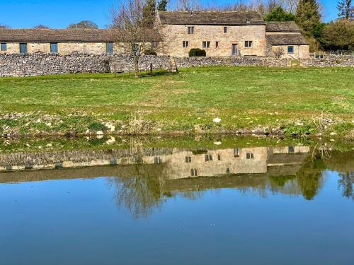 an old stone building is reflected in a pond at Priest Hill-Rxx7 in Stanton in Peak
