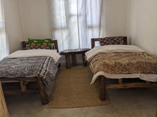 a room with two beds and a table and a window at Giraffe Gallery Home in Arusha
