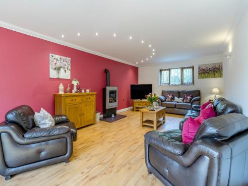 a living room with leather furniture and a red wall at Derwen Haidd in Llanafan