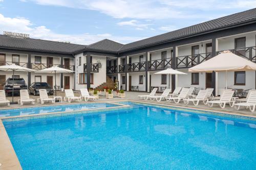 a pool in front of a hotel with chairs and umbrellas at ROMANTIK in Solotvyno