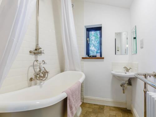a white bathroom with a tub and a sink at Pettingalls Farm Cottage in Great Ellingham