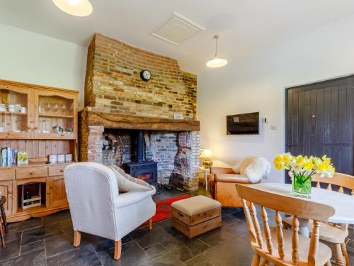 a living room with a fireplace and a table and chairs at Pettingalls Farm Cottage in Great Ellingham