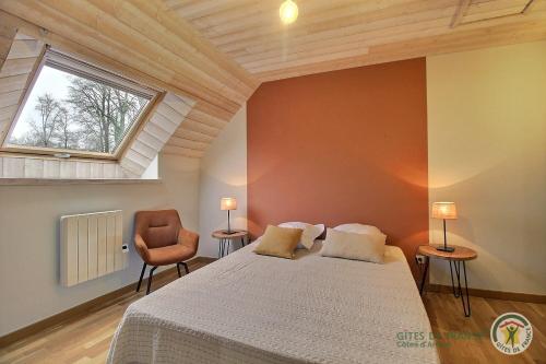 a bedroom with a bed and a window and a chair at La maison des charretiers in Cohiniac