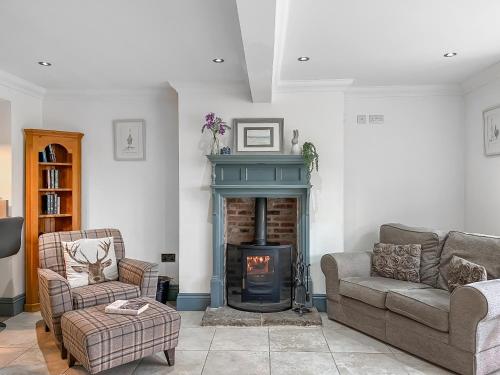 a living room with a fireplace and a couch and chairs at Old Master's Cottage in Leven